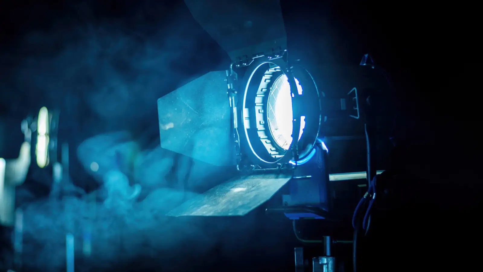 A film light with barn doors glowing blue through haze on an Indie Crate set