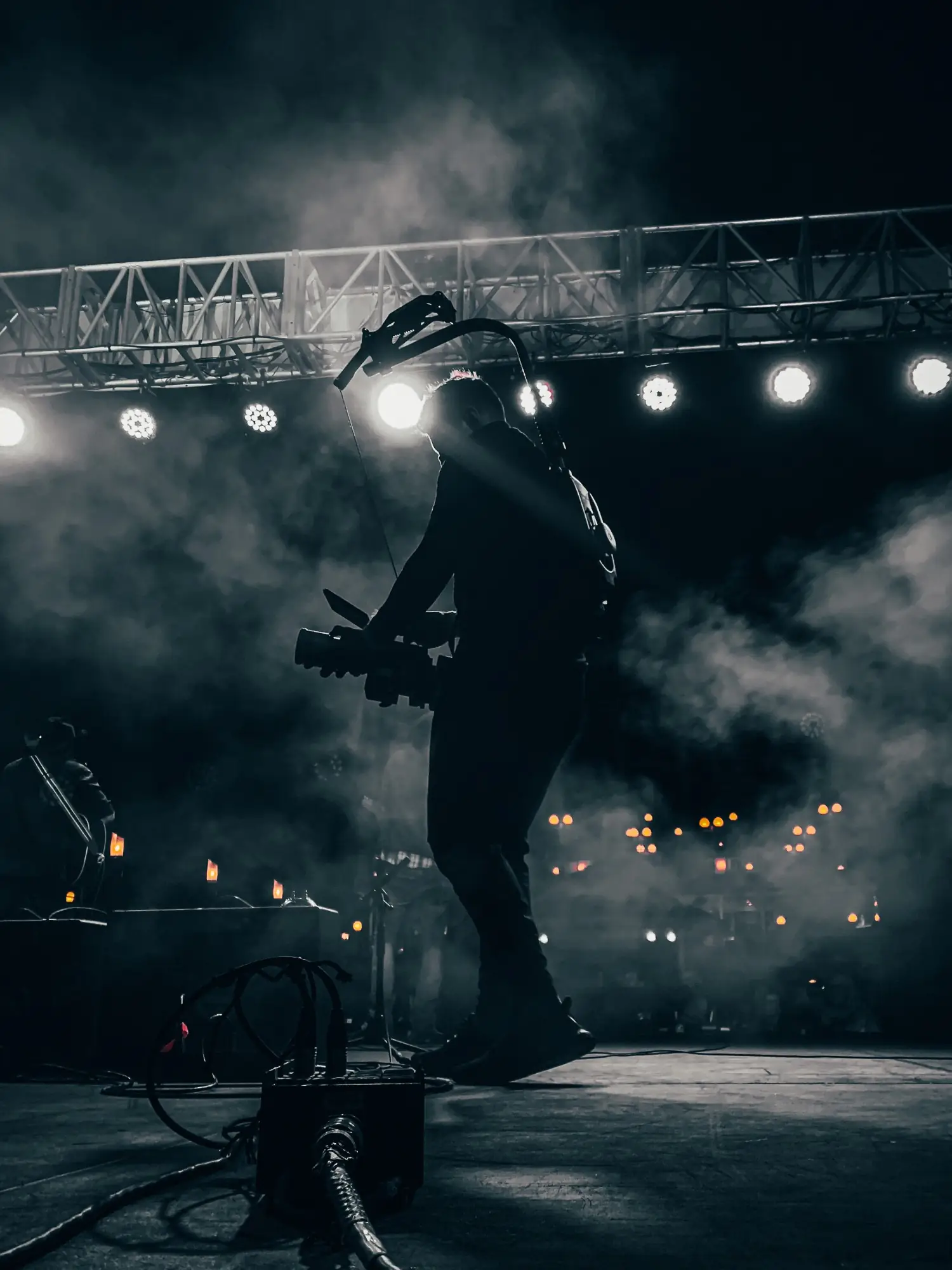 Silhouette of an Indie Crate camera operator filming on a smoky concert stage under truss lights